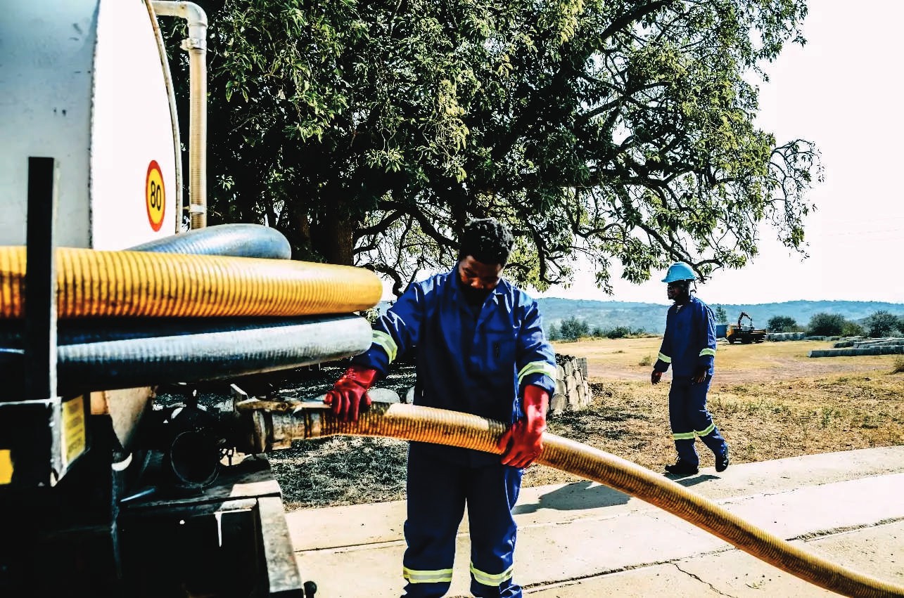 Operator in overalls handling a honey sucker hose